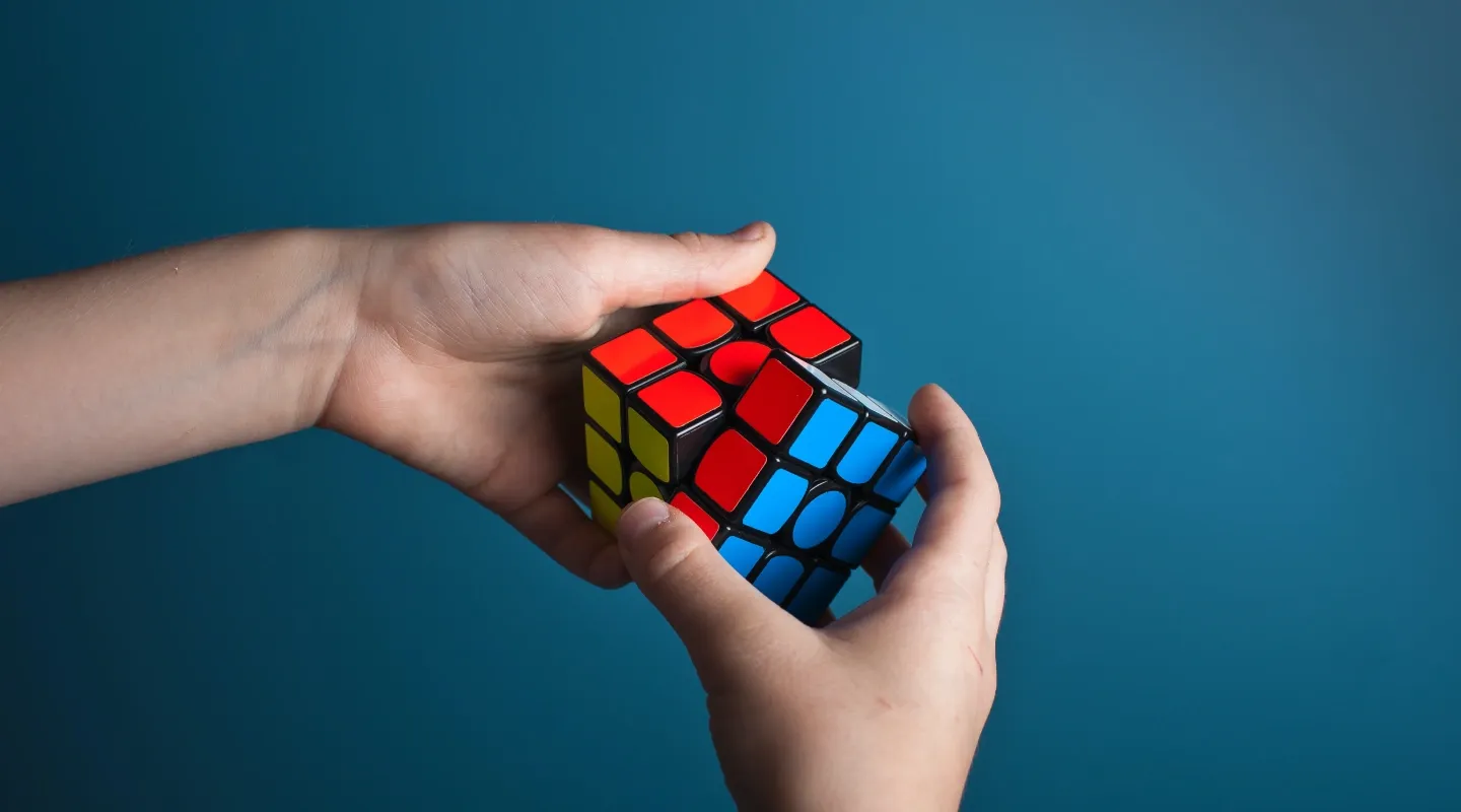 Un par de manos intentando resolver un cubo de Rubik.