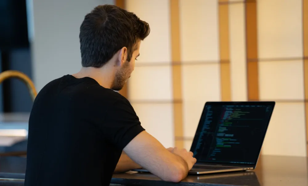 Hombre trabajando sen frente a una laptop.